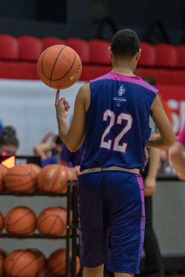 The image shows a basketball player from behind, who is spinning the ball on his finger.